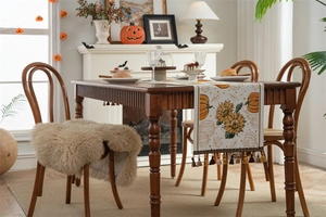 Detail of autumn table runner with sunflower and pumpkin patterns and fringe tassels