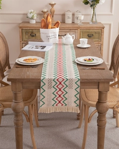 Detail of hand-woven table runner featuring red and green geometric waves with tassels