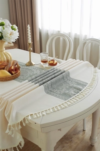 Close-up of vintage floral jacquard tablecloth with delicate fringe and woven texture