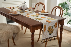 Detail of harvest pumpkin sunflower table runner with tassels on dark wooden table