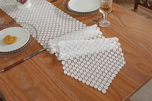 Close-up of white hollow lace table runner with dot mesh pattern on a wooden table