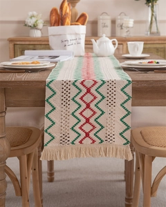 Detail of hand-woven cotton linen table runner with red and green zig-zag patterns and tassels