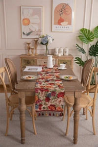 Close-up of vintage floral jacquard table runner with decorative tassel trim on wood table