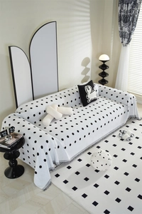 Detailed view of jacquard chenille sofa cover with black polka dots and white tassel trim