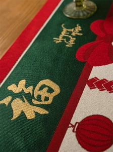 Detail of red festive table runner with golden jacquard Fu character and tassel accents