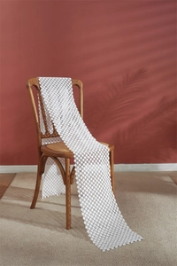 Detail of white crochet hollow floral lace table runner draped over a vintage wooden chair