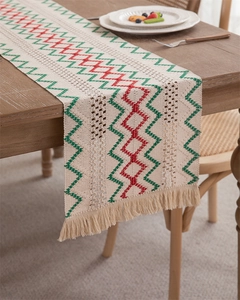 Detail of woven table runner featuring red and green zigzag patterns and tassel edges