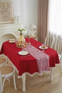 Close-up of red jacquard floral tablecloth with vintage white fringe tassels on edges