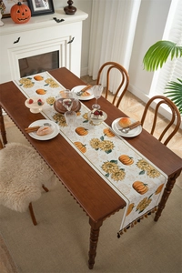 Detail of harvest table runner with pumpkin and sunflower patterns and decorative tassels