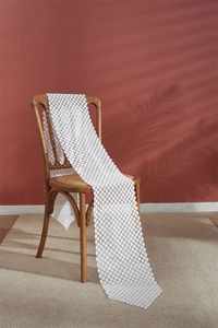 Close-up of white hollow lace table runner with polka dot pattern on wooden chair