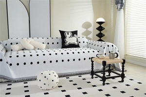 Close-up of chenille sofa cover showing black polka dot pattern and fringe detail edges