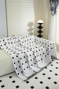 Detail of Nordic chenille sofa throw with black polka dots and fringe tassels decor