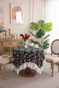 Detailed close-up of white floral embroidery and ruffled edges on black cotton tablecloth