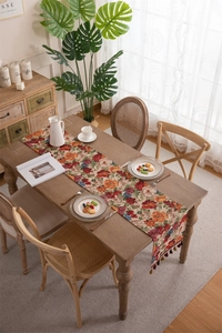 Detail of vintage floral jacquard table runner with decorative brown fringe tassels