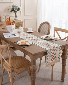 Detail view of bohemian woven cotton table runner with red green zigzag pattern and fringe