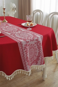 Detailed view of red retro jacquard tablecloth with white ethnic patterns and fringe trim