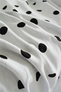 Macro detail of Nordic chenille sofa cover showing black polka dots on white fabric