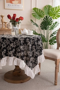 Detail of French cotton tablecloth with white floral embroidery and ruffled edge decor