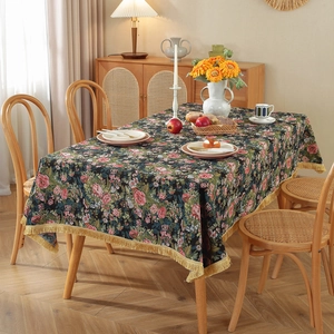 Vintage floral jacquard tablecloth with gold tassels on a rectangular wooden dining table