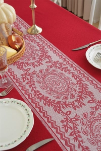 Close-up of red jacquard table runner with white embroidery and festive tassels