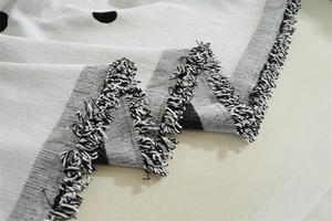 Detail of chenille sofa cover showing black polka dot jacquard pattern and fringe edge