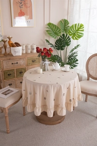 Detail of cream cotton tablecloth with animal embroidery and elegant ruffled edges