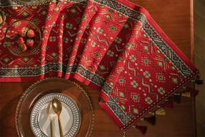 Dettaglio del runner da tavola rosso con motivi jacquard etnici e eleganti nappe bicolori
