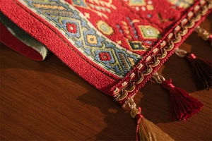 Dettaglio del runner da tavolo rosso con motivi etnici geometrici e finiture a nappe