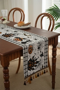 Macro detail of Halloween table runner with pumpkins and bats featuring tassel trim