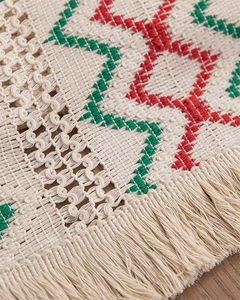 Detailed close-up of woven cotton linen table runner with red green embroidery and tassels