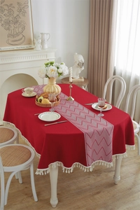 Detailed shot of red jacquard tablecloth with white tassel edge and geometric pattern