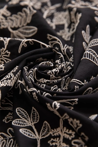 Macro shot of French cotton tablecloth featuring leaf embroidery and ruffled edge details