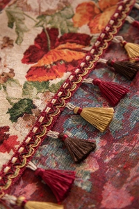 Close-up of vintage floral jacquard fabric with elegant red and gold fringe tassels