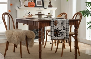 Detailed view of Halloween table runner with pumpkin and bat patterns and fringe tassels