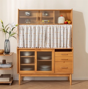 Close-up of kitchen cabinet featuring white polka dot curtain and reeded glass doors