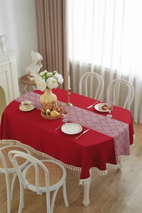 Detailed view of red jacquard tablecloth featuring white tassels and geometric table runner