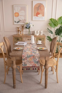 Close-up of retro floral table runner with colorful tassels on a rustic wooden table