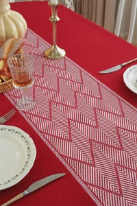 Detail of red jacquard table runner with white geometric patterns and tassel accents
