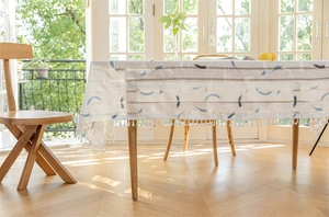 Detail der cremefarbenen Quasten und blauen Halbmonddrucke auf einer Tischdecke
