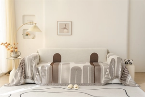 Close-up of chenille sofa cover showing brown geometric patterns and tassel fringe detail