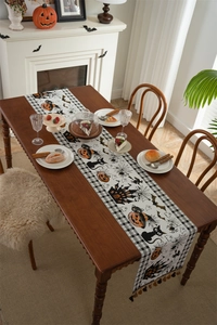 Detail of Halloween table runner with black cats and pumpkins on wooden dining table