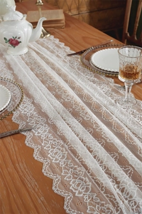 Detailansicht des weißen Spitzen-Tischläufers mit Rosenmuster und gewelltem Randdekor
