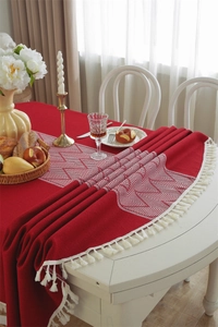 Detail of red jacquard tablecloth with white geometric patterns and tassel fringe edge