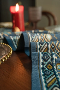 Dettaglio del runner da tavola jacquard con motivi etnici geometrici su tavolo in legno