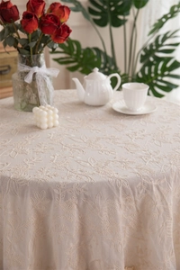 Close-up of intricate floral embroidery on beige waterproof cotton tablecloth with frilled edges