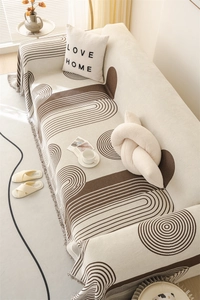 Detail of Nordic chenille sofa cover with brown geometric patterns and tassel edges
