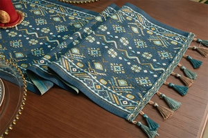 Dettaglio runner da tavola bohémien con motivi jacquard geometrici e nappe colorate