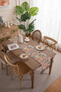 Detail of floral jacquard table runner with decorative colorful tassel fringe accents