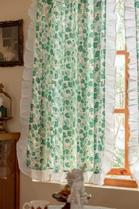 Detail of cotton curtain featuring green leaf prints and elegant white ruffle edges