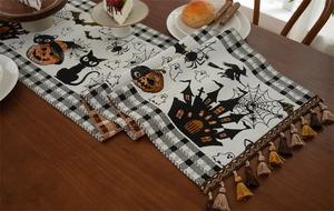 Close-up of Halloween table runner with witch cat, pumpkin prints and colorful tassels